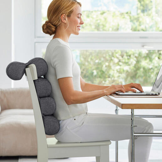 Femme assise avec un coussin flexible à un bureau, travaillant sur un ordinateur portable.