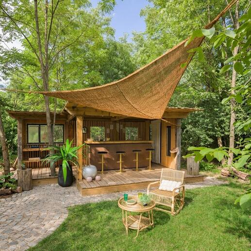 Voile solaire en fibres de coco au-dessus d'une terrasse en bois avec des tabourets de bar.