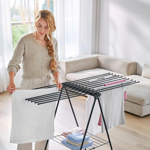 Femme organisant du linge sur un étendoir à linge design dans le salon