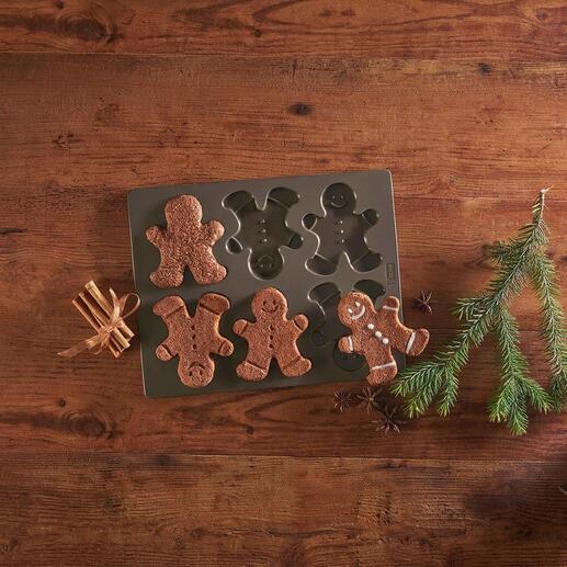 Moule à biscuits en pain d'épices avec des bonhommes en pain d'épices cuits sur une table.