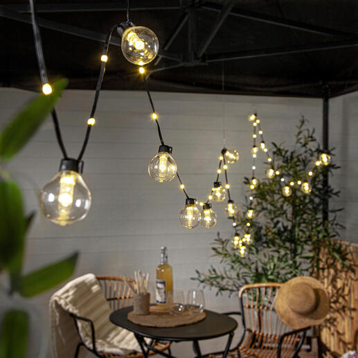 Guirlande lumineuse au-dessus d'une table avec des chaises en extérieur.