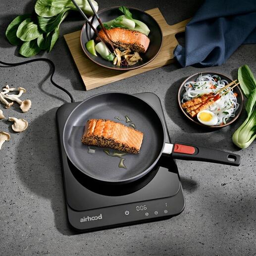 Plaque à induction ultra fine avec une poêle et du saumon grillé.