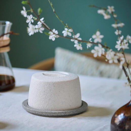 Beurrier en céramique sur une table avec des fleurs et une cafetière.