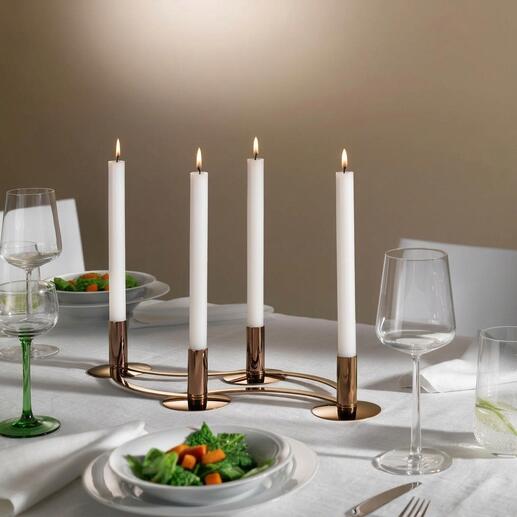 Bougeoir variable avec quatre bougies blanches sur une table dressée.