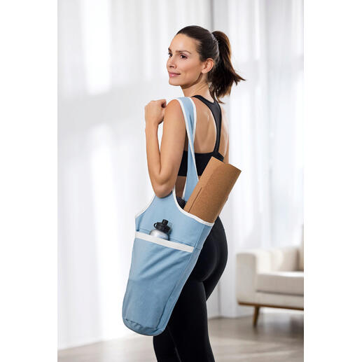 Femme portant un sac de yoga avec un tapis de yoga et une bouteille d'eau.