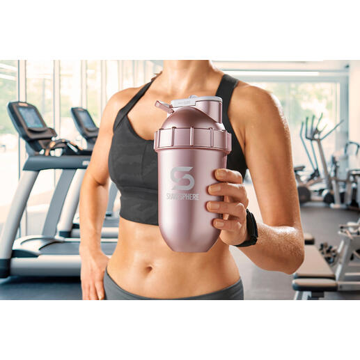 Femme tenant un shaker rose dans une salle de sport.