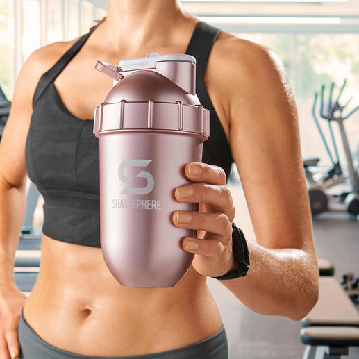 Femme tenant un shaker rose dans une salle de sport.