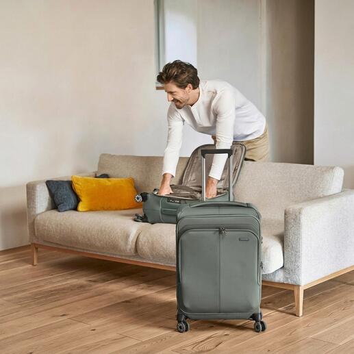 Homme range une valise légère Travelite sur un canapé.