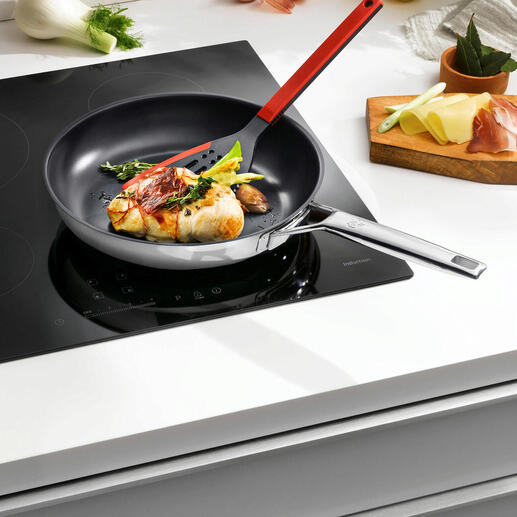 Poêle en acier inoxydable avec effet antiadhésif, remplie de légumes et de poisson sur une cuisinière.