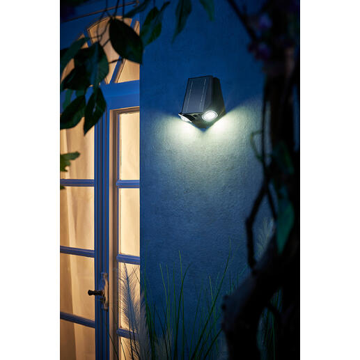 Lampe solaire intelligente sur un mur à côté d'une porte la nuit