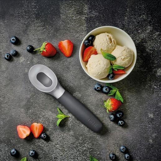 Cuillère à glace à côté d'un bol avec différents parfums de glace et des fruits.