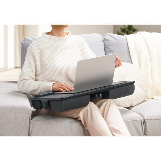 Personne avec un coussin pour ordinateur portable 2-en-1 sur les genoux, servant de table.