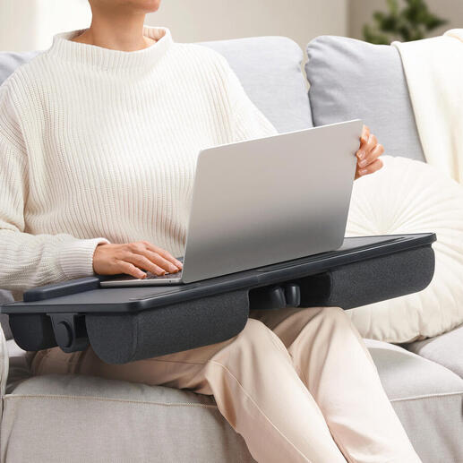 Personne avec un coussin pour ordinateur portable 2-en-1 sur les genoux, servant de table.