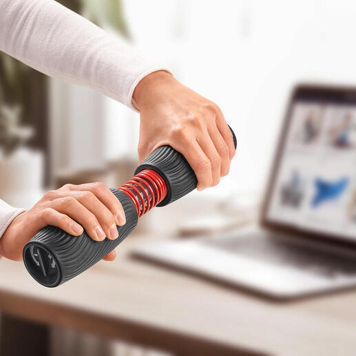 Personne s'entraîne avec un entraîneur de poignet et d'avant-bras sur une table avec un ordinateur portable.