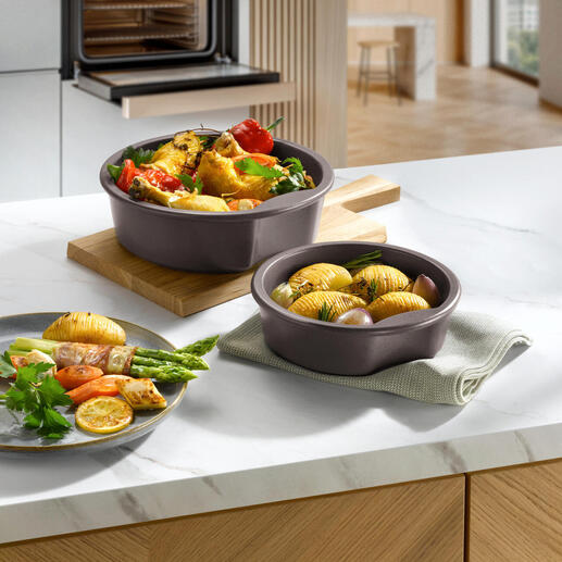 Deux pots celtes avec des légumes et des pommes de terre sur une assiette en bois dans une cuisine moderne.