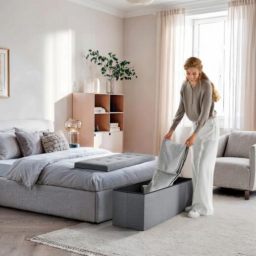 Coffre à siéger pliable en gris foncé, utilisé dans la chambre.