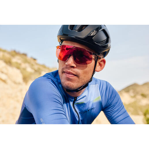 Cycliste portant des lunettes de soleil sport rouges et un casque noir sur un sentier.