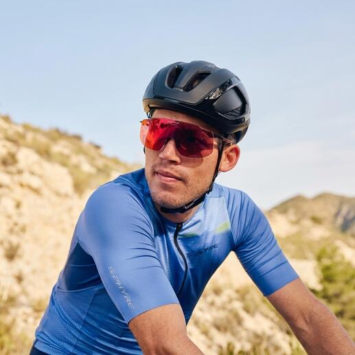 Cycliste portant des lunettes de soleil sport rouges et un casque noir sur un sentier.