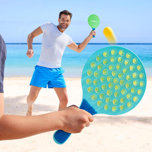Homme jouant sur la plage avec une raquette ovale et frappant la balle.
