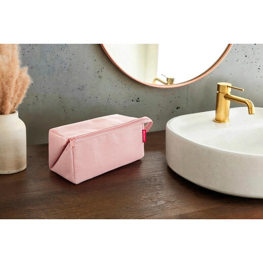 Nécessaire de voyage 2-en-1 rose sur une table en bois à côté d'un lavabo