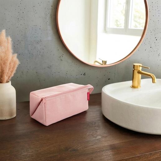 Nécessaire de voyage 2-en-1 rose sur une table en bois à côté d'un lavabo