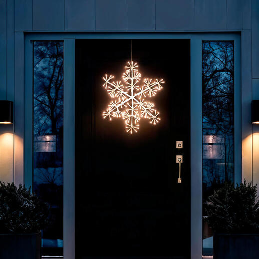 Flocon de neige LED éclairé à l'extérieur, suspendu devant une porte d'entrée.