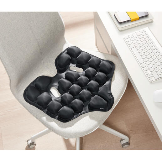 Coussin ergonomique noir sur une chaise.