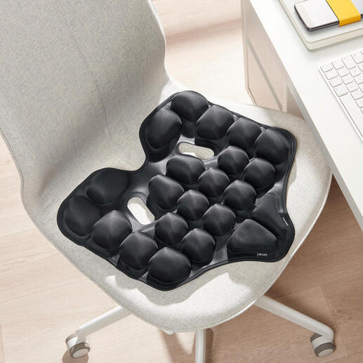 Coussin ergonomique noir sur une chaise.