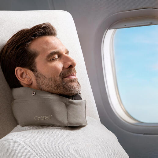 Homme avec un coussin de voyage se détend près de la fenêtre dans l'avion.