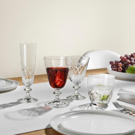 Deux verres au design Eaton sur une table, entourés de raisins et d'une table dressée.