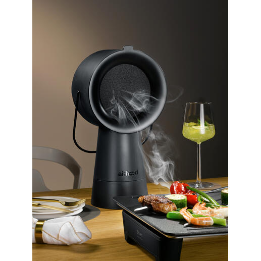Airhood 2.0 en noir, appareil à griller fumant sur une table avec légumes et viande.