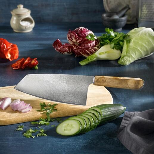 Couteau Nakiri en damas sur une planche en bois, entouré de légumes frais.
