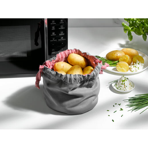 Sac à pommes de terre gris avec des pommes de terre et des herbes sur la table.