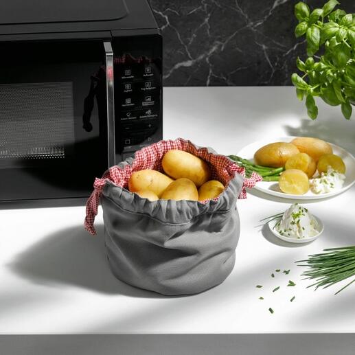Sac à pommes de terre gris avec des pommes de terre et des herbes sur la table.