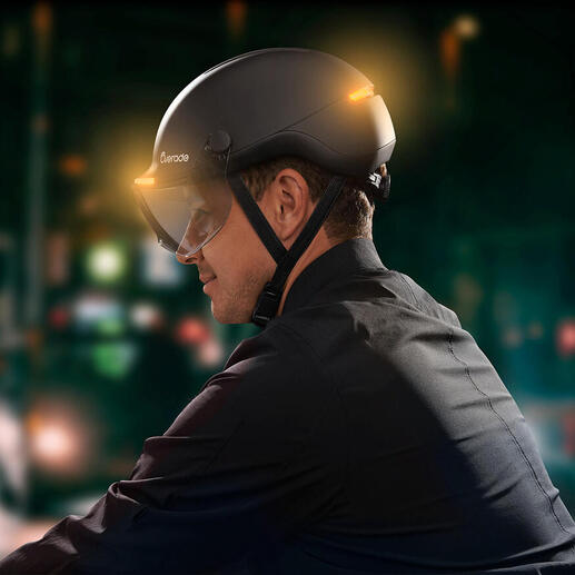Homme portant un casque de vélo avec signal lumineux dans la ville la nuit