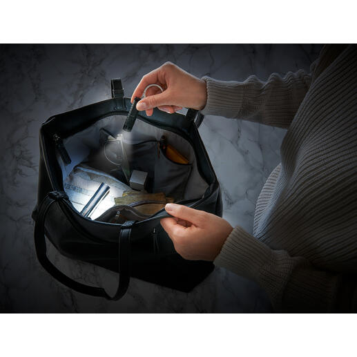 Deux mains tenant une lampe de poche micro intelligente dans un sac