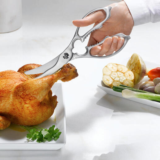 Ciseaux de cuisine et de volaille 2-en-1 coupant un poulet sur une assiette.