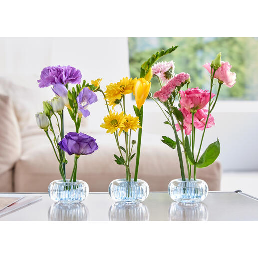 Trois mini-vases avec des fleurs colorées sur une table.