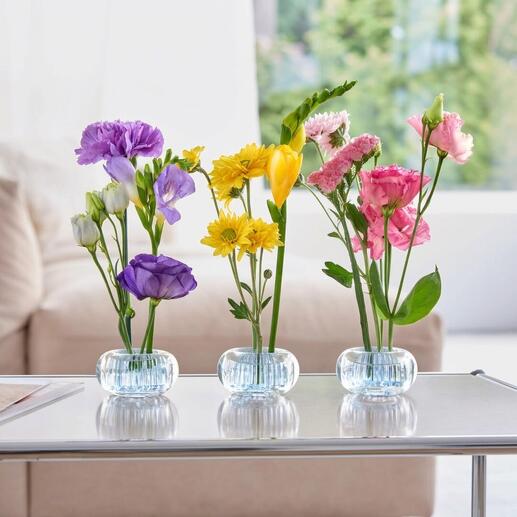 Trois mini-vases avec des fleurs colorées sur une table.