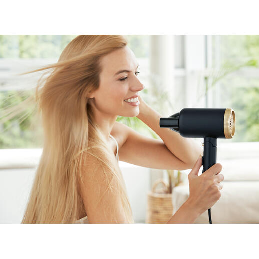 Sèche-cheveux de voyage compact en utilisation, femme en train de sécher ses cheveux.