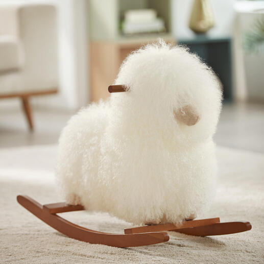Bébé en peluche en peau de mouton blanche sur un tapis.