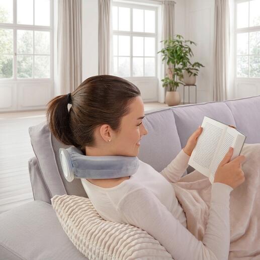 Femme se détend avec un coussin thermique et lit sur le canapé.