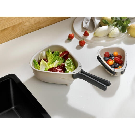 Passoire de cuisine compacte avec des légumes et des fruits frais en arrière-plan.