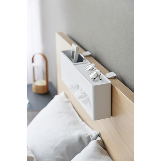 Boîte de mouchoirs blanche sur la tête de lit avec des lunettes et un smartphone.