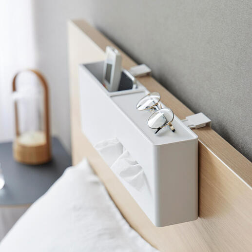 Boîte de mouchoirs blanche sur la tête de lit avec des lunettes et un smartphone.