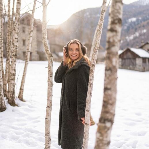 Femme avec des écouteurs en alpaga devant des bouleaux dans la neige.