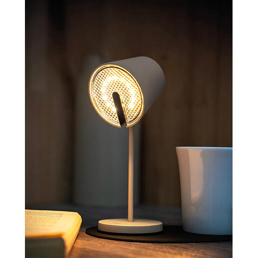 Lampe magnétique noire avec lumière claire, posée sur une table à côté d'une tasse.