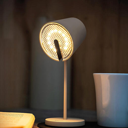 Lampe magnétique noire avec lumière claire, posée sur une table à côté d'une tasse.