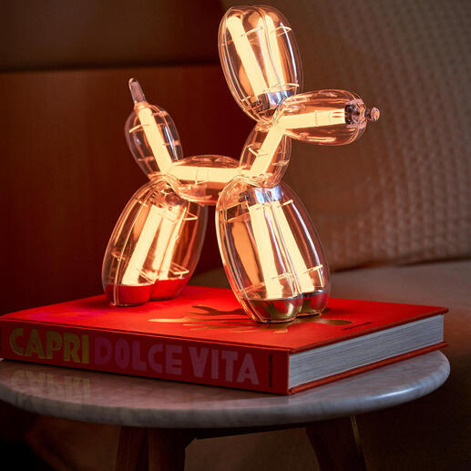 Lampe en forme de chien en ballon sur un livre, lumière blanche chaude.