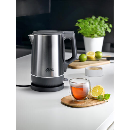 Bouilloire double avec finition en acier inoxydable et thé dans un bol en verre sur la table.